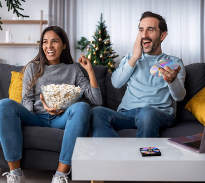 Afbeelding van een man en vrouw die popcorn eten en een film kijken - de externe dvd/cd-speler staat op tafel - ze lachen en genieten